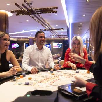 Ambiance conviviale à la table de jeu : trois clients s'entretiennent avec la croupière du casino Schaanwald, aménagé avec goût.