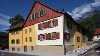Maison traditionnelle Landweibels-Huus à la façade jaune et rouge sur fond de montagnes au Liechtenstein. Maison traditionnelle Landweibels-Huus à la façade jaune et rouge sur fond de montagnes au Liechtenstein.