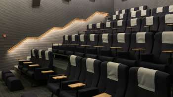 Salle de cinéma moderne au Skino de Schaan avec des sièges confortables, des petites tables et un éclairage tamisé.