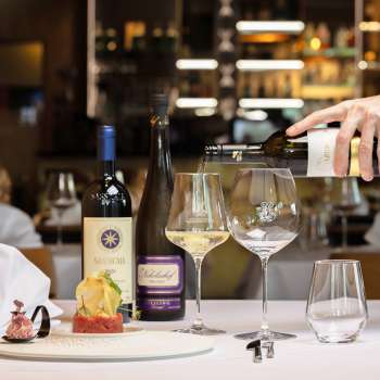 Un serveur sert du vin blanc pour accompagner un plat élégamment présenté au restaurant Alpspitz.