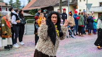 Sorcière déguisée de Schaan lors du défilé de carnaval à Schaan, Liechtenstein, devant un public et des confettis colorés dans la rue