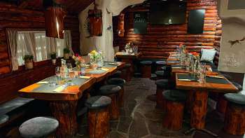 Vue sur un restaurant à l'aménagement rustique avec des meubles en bois, des tables décorées en vert et des bougies