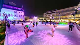 Personnes patinant sur la patinoire éclairée de Vaduz on Ice dans le centre-ville de Vaduz le soir