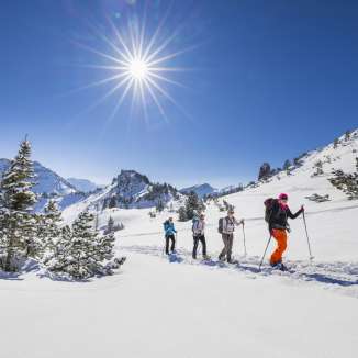 Groupe lors de randonnées en raquettes à travers le paysage enneigé du Schönberg près de Malbun sous un soleil d'hiver radieux.