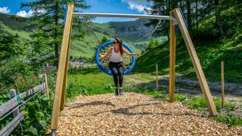 Une femme se balance dans les montagnes du Liechtenstein et profite de la vue