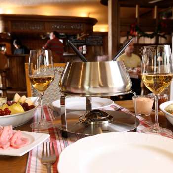 Gros plan sur un service à fondue au fromage avec du pain frais, des légumes et du vin dans une ambiance élégante