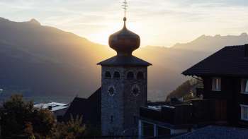 Clocher à bulbe de l'église paroissiale Saint-Joseph avec le soleil couchant en arrière-plan