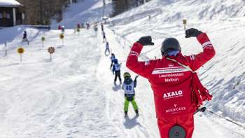 Cours de ski au parc Malbi à Malbun avec des casques colorés et des moniteurs engagés - apprendre en toute sécurité dans un environnement adapté aux enfants