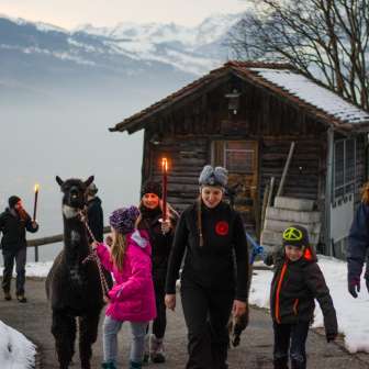 Trekking familial avec des lamas dans la neige au Liechtenstein, avec des torches et une vue sur les montagnes - une expérience particulière de fondue en plein air.