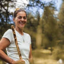 Guide de randonnée au Liechtenstein lors d'une visite guidée dans la nature Guide de randonnée sympathique avec un bâton de marche lors d'une randonnée nature au Liechtenstein, entourée d'arbres et d'un paysage estival.