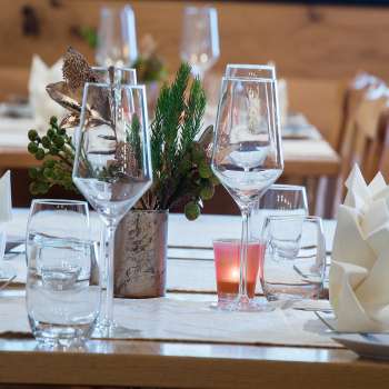 Gros plan sur une table joliment dressée avec des verres, des couverts et une petite décoration végétale.