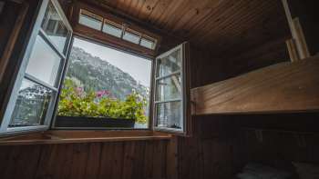 Vue de la fenêtre du dortoir : vue d'un dortoir simple avec lits superposés du refuge Gafadurahütte sur le paysage de montagne.