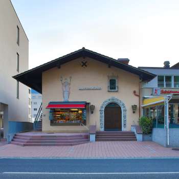 Vue extérieure de l'ancien cinéma Vaduz avec lettrage au-dessus de l'entrée et auvents rouges, situé entre deux bâtiments modernes.