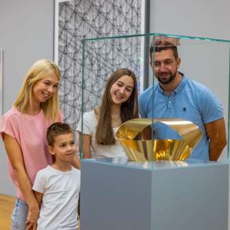 Une famille contemple une sculpture en or au Kunstmuseum Liechtenstein - le plaisir de l'art pour petits et grands au cœur de Vaduz.
