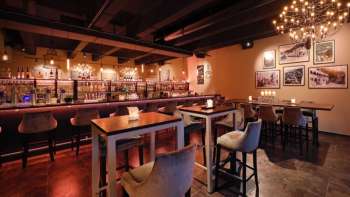 Intérieur élégant du restaurant avec des éléments en bois foncé, un espace bar et des chaises confortables dans une ambiance chaleureuse.