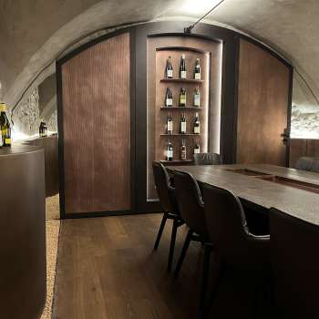 Elégante salle de dégustation du WY Weinbar avec plafond voûté et table en bois noble pour des dégustations de vin exclusives.