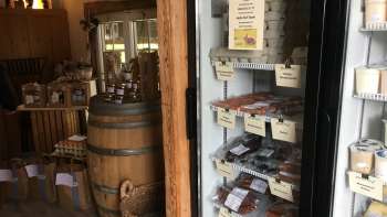 Assortiment régional dans la boutique de la ferme Hedihof – réfrigérateur avec produits de viande emballés et salle de vente rustique.