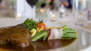 Détail d'un plat principal avec des légumes verts, du bacon et une sauce crémeuse dans l'assiette