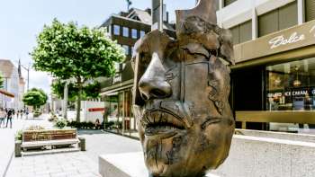 Sculpture moderne en bronze représentant un visage dans la zone piétonne de Vaduz.