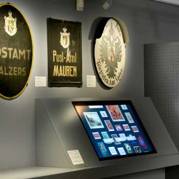 Salle du musée avec d'anciennes plaques postales et un affichage numérique sur l'histoire de la poste au Liechtenstein.