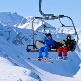 Deux enfants avec leur équipement de ski traversent les montagnes enneigées de Malbun en télésiège.