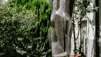 Sculpture moderne de personnages en bronze, debout parmi des fleurs et des arbustes à Vaduz - œuvre de Herbert Albrecht.