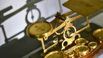 Image d'une balance à fléau antique dorée avec différents poids, exposée au PostMuseum à Vaduz.