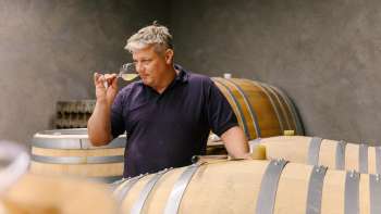 Vigneron du domaine Hoop au Liechtenstein en train de déguster le vin directement du fût en bois dans la cave à vin.