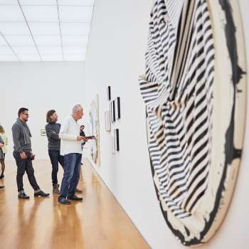 Groupe de visiteurs dans la salle d'exposition du Musée des Beaux-Arts, au premier plan une grande œuvre d'art ronde