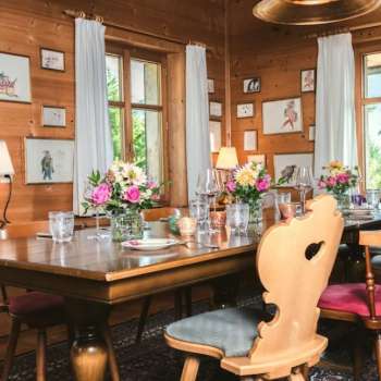 Salle de restaurant accueillante avec plafond en bois, table décorée avec soin et vue sur les fenêtres lumineuses
