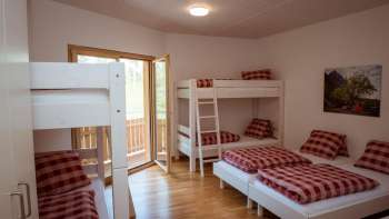 Chambre familiale à plusieurs lits avec lits superposés et lits simples dans la maison d'hôtes au camping Mittagsspitze.
