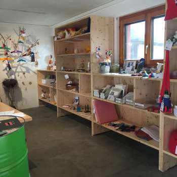 Intérieur du magasin Birkahoflädile avec des étagères en bois remplies de produits régionaux, décorées avec des éléments colorés - magasin à la ferme au Liechtenstein.