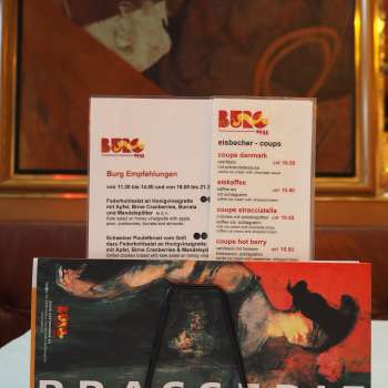 Menu de la Brasserie Burg devant une fresque murale colorée - art culinaire et art au cœur de Vaduz.