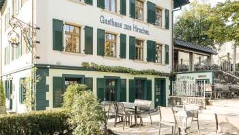 Terrasse accueillante avec tables et chaises en bois devant l'Gasthaus zum Hirschen