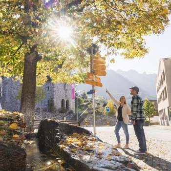 Scène automnale avec un panneau indicateur de sentier de randonnée au centre de Triesenberg
