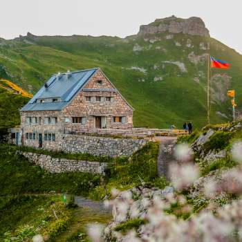 Gros plan sur le refuge Pfälzer avec le drapeau du Liechtenstein dans une ambiance de soirée.