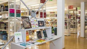 Entrée lumineuse de la Bibliothèque nationale du Liechtenstein avec des étagères modernes et un espace d'exposition pour les nouvelles publications