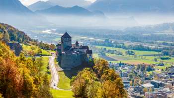 Château de Vaduz avec vue sur la vallée du Rhin et le paysage montagneux.