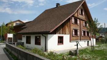 Küefer-Martis-Huus historique avec façade traditionnelle en bois et volets rouges à Ruggell, Liechtenstein.