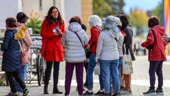 Visite guidée City-ClassicTour dans la ville de Vaduz Groupe de touristes avec guide en manteau rouge lors d'une visite guidée du centre de Vaduz au Liechtenstein