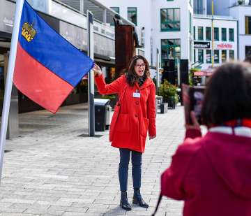 Une guide présente le drapeau du Liechtenstein lors d'une visite guidée dans le centre de Vaduz