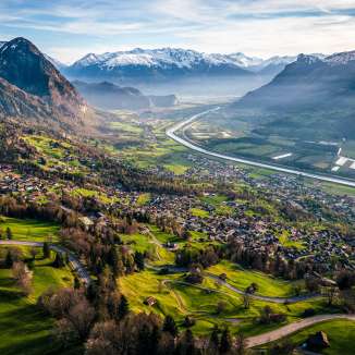 Vue lointaine du versant sur la vallée du Rhin avec des champs, des villages et des montagnes enneigées - nature idyllique au Liechtenstein