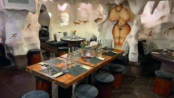 Gros plan sur un restaurant confortablement aménagé avec des tables et des chaises en bois, décoré de fleurs et de bougies.