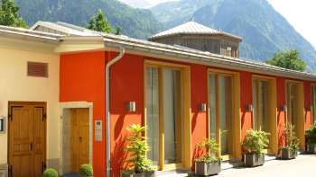 Vue extérieure du centre culturel Gasometer avec une façade colorée et un panorama alpin en arrière-plan.