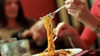 Une personne ramasse des spaghettis avec une fourchette dans une assiette à la Brasserie Burg