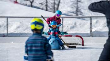 Famille patinant à Malbun, enfant assis sur un patin à glace en forme d'animal.
