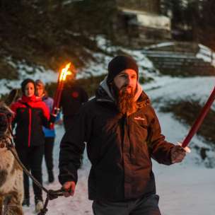 Groupe lors d'une randonnée guidée en lama dans le Liechtenstein enneigé avec des torches - une aventure en plein air pleine d'ambiance pour petits et grands.