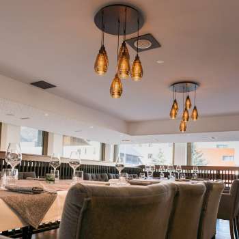 Espace de restauration à l'aménagement moderne avec vue sur la baie vitrée et lampes suspendues de style.