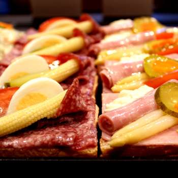 Tartines de charcuterie, fromage, œufs et légumes dans la vitrine de la pâtisserie Balu