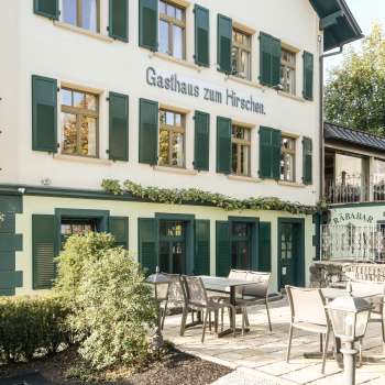 Terrasse accueillante avec tables et chaises en bois devant l'Gasthaus zum Hirschen